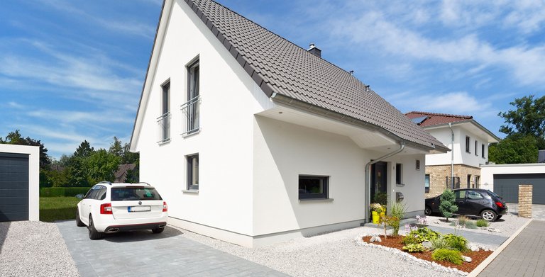 Weißer Putz, graue Fensterrahmen und Dachziegel – so präsentiert sich das massiv gebaute Einfamilienhaus.  Copyright: Heinz von Heiden GmbH Massivhäuser