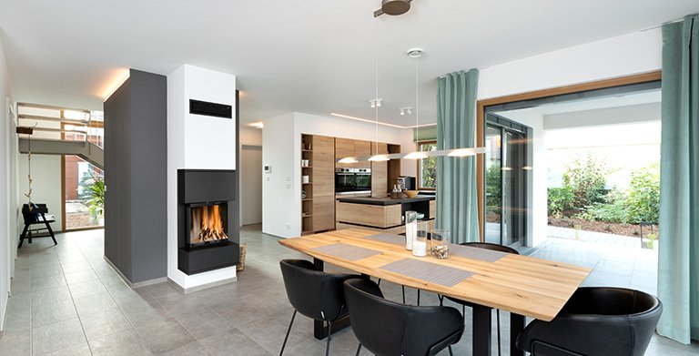 Offener Wohnbereich mit großzügigem Platzangebot und Kaminofen "Kingfire Grande S" von Schiedel Copyright: TALBAU-Haus GmbH