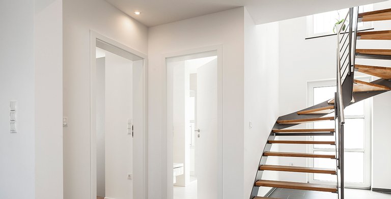 Der Treppenaufgang ins Obergeschoss erfolgt über eine elegant gewendelte Treppe Copyright: Wolf-Haus