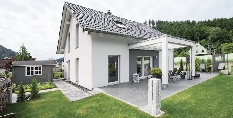 Die Farbgestaltung von weißer Hausfassade und dunklem Satteldach bildet einen modernen Kontrast. Copyright: WeberHaus